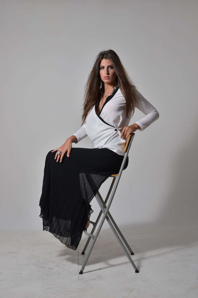 A black pleated maxi skirt with a white blouse.