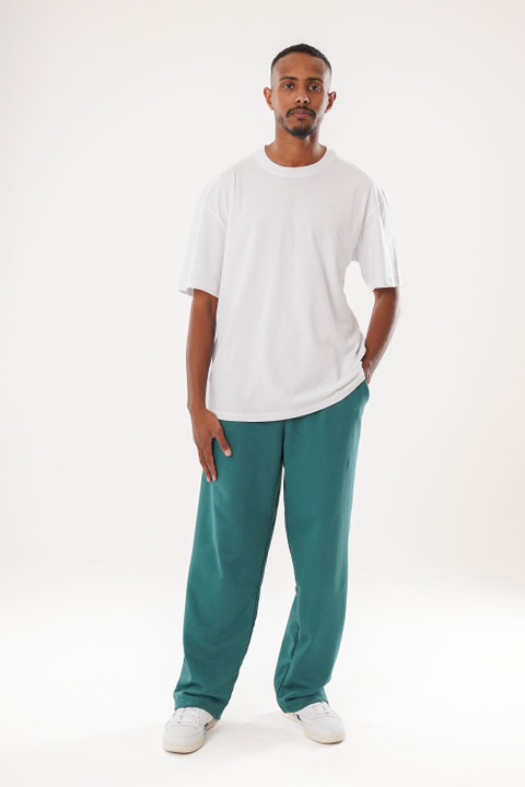 An oversized white tee with teal trousers.