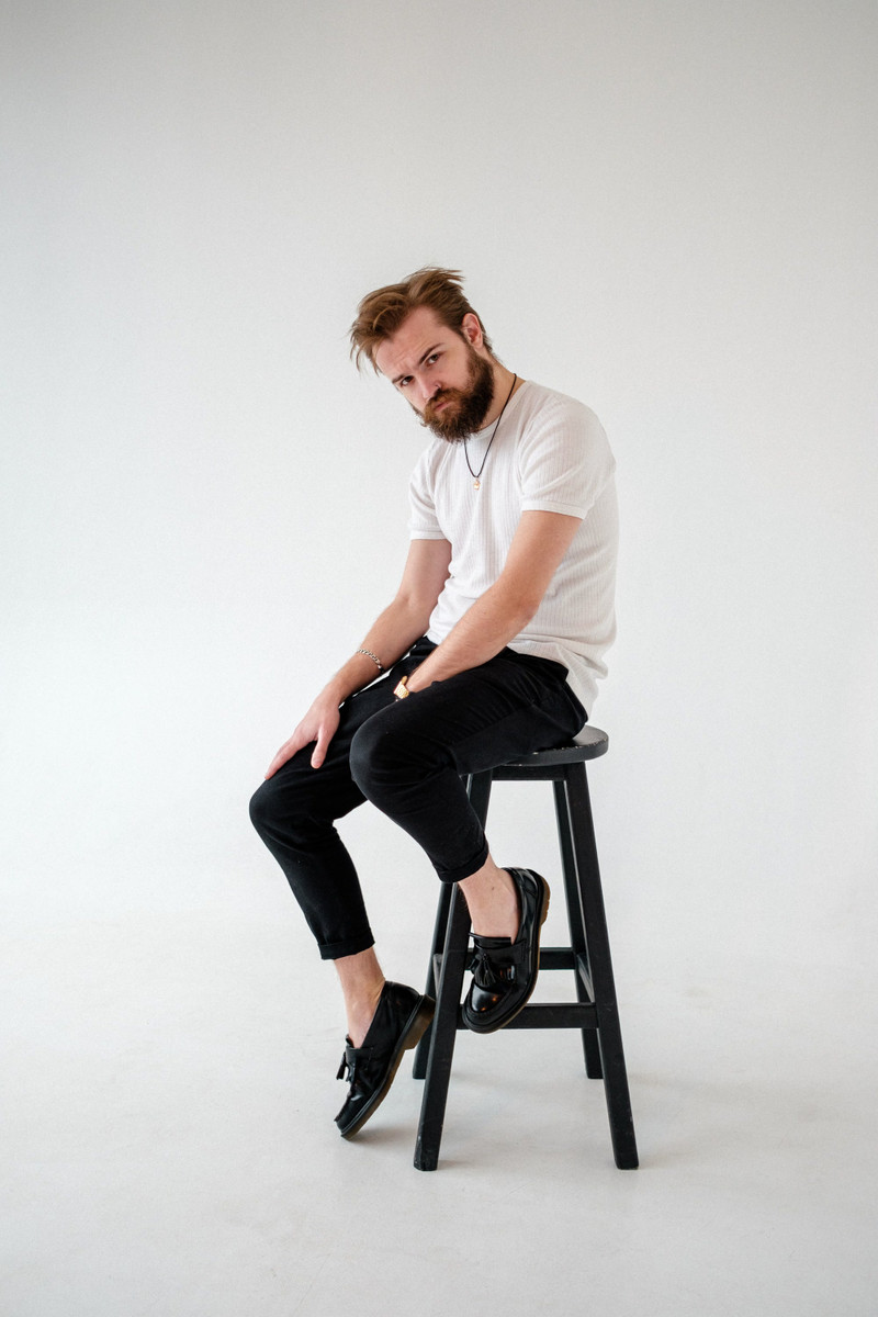 The white crew tee, seated on a stool.