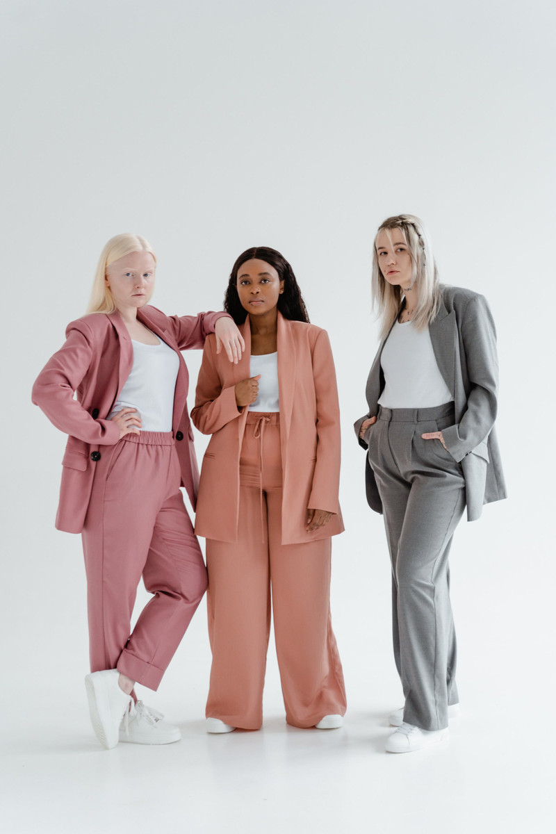 Three women in relaxed suits in rose, coral and grey.