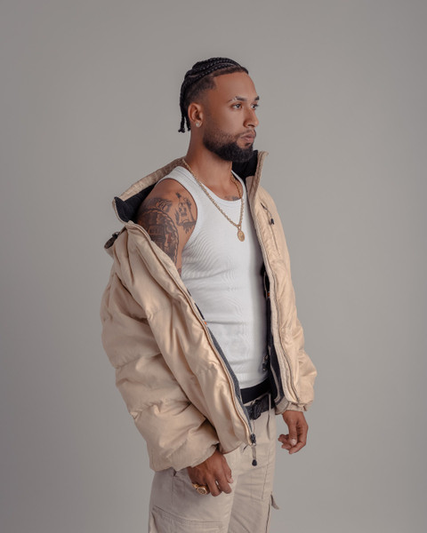 The cream puffer jacket open over a white vest.