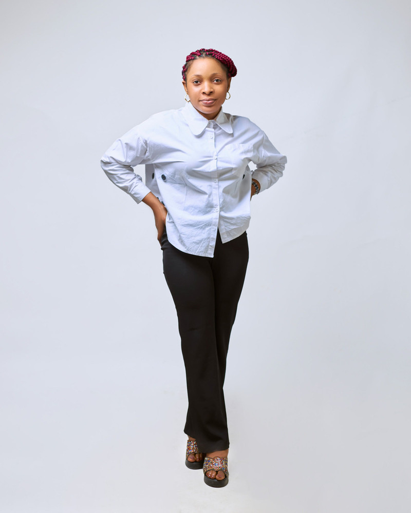 A pale blue oxford shirt worn loose over trousers.