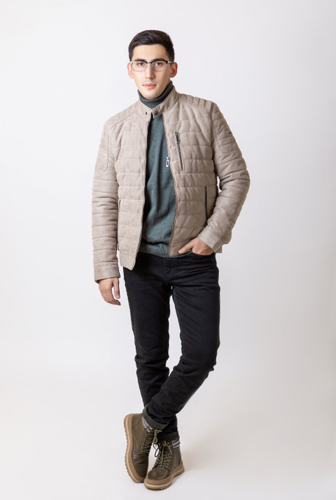 A stone quilted jacket over a grey sweater.